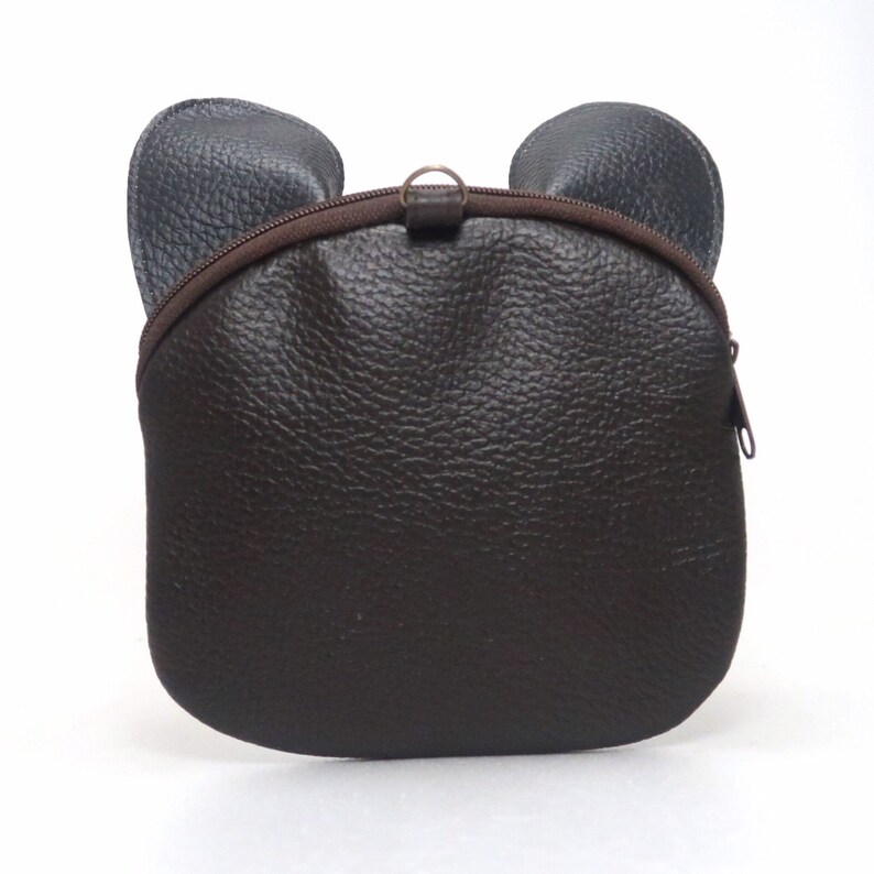 K&ouml;nnte beinhalten: Eine braune Lederhandtasche mit B&auml;renohren. Die Tasche hat einen Rei&szlig;verschluss und einen braunen Rei&szlig;verschluss-Schieber.