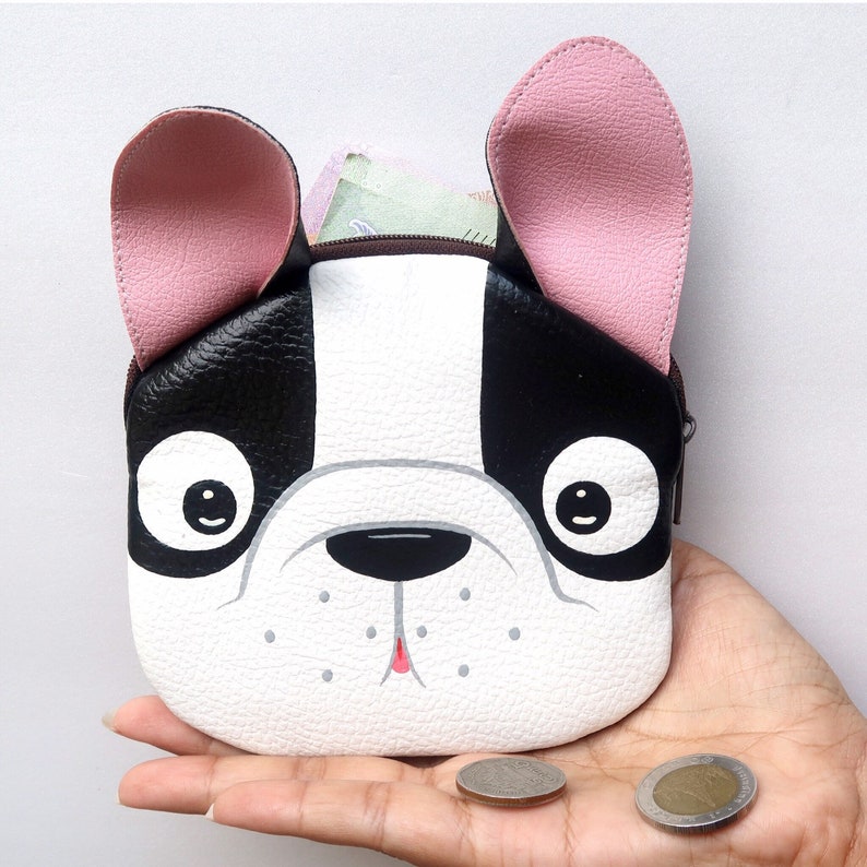 K&ouml;nnte beinhalten: Eine kleine schwarze und wei&szlig;e Geldb&ouml;rse in Form einer franz&ouml;sischen Bulldogge mit rosa Ohren. Die B&ouml;rse ist aus Kunstleder und hat einen Rei&szlig;verschluss.