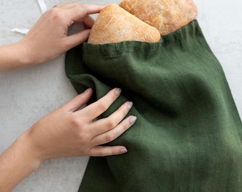 May include: A green linen bag with a drawstring closure, being used to hold three loaves of bread.