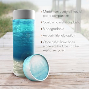 May include: A biodegradable cremation urn made from natural paper components. The urn features a blue and white ocean scene and is designed to be scattered in water. The text on the image reads: "Made from sturdy all natural paper components", "Contain no metal or plastic", "Biodegradable", "An earth friendly option", "Once ashes have been scattered, the tube can be kept or recycled".