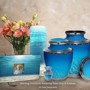 May include: A set of blue and silver cremation urns with a water-like design. The urns are available in different sizes and include a matching guestbook, scattering tube, and keepsake.