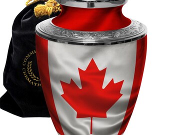 May include: Silver cremation urn with a red and white Canadian flag design. The urn has a silver lid with a small Canadian flag on top. The urn is sitting on a black velvet bag with gold trim.