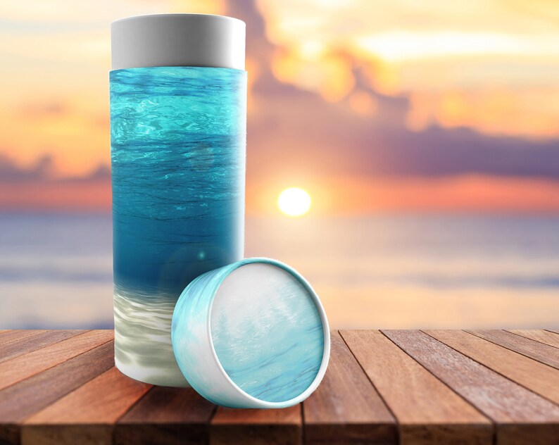 May include: A white cardboard tube with a blue and white ocean-themed design. The tube is lying on a wooden surface.