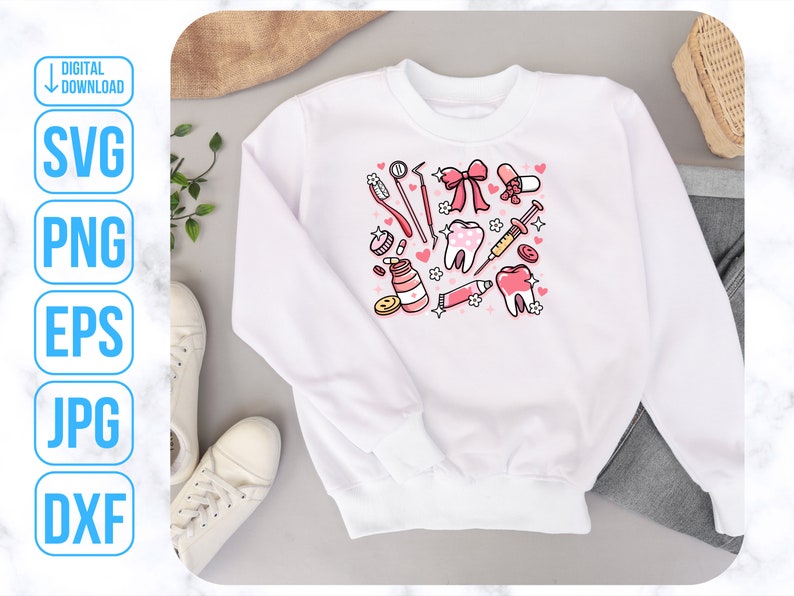 Op de afbeelding: Wit sweatshirt met een roze en rood ontwerp met verschillende tandheelkundige instrumenten, waaronder tandenborstels, floss en een spuit. Het ontwerp bevat ook harten en tanden.