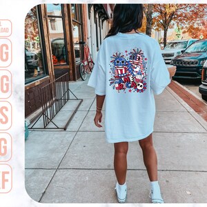 May include: A light blue t-shirt with a colorful graphic design featuring fireworks, stars, and the word "America".