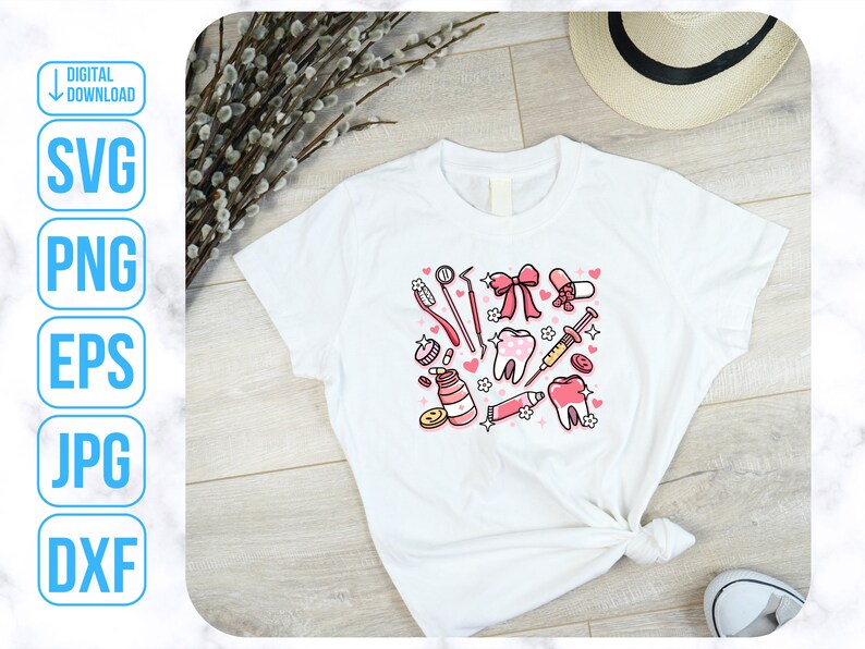 Op de afbeelding: Wit T-shirt met een roze en wit ontwerp van tandheelkundige instrumenten, waaronder een tandenborstel, tandpasta, floss en een spuit. Het ontwerp bevat ook een roze strik en harten.