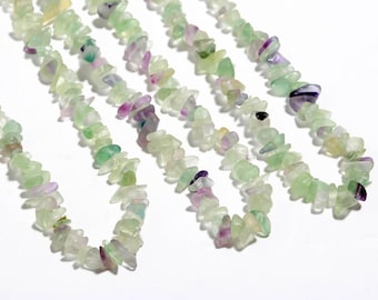 May include: Strands of gemstone beads in shades of green, purple, and white. The beads are small, irregular chips, strung together to create a necklace or bracelet. The background is plain white.