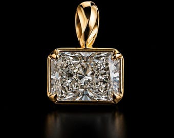 Peut inclure: Un pendentif en or jaune poli serti d'une pierre précieuse transparente de taille radiant rectangulaire. La pierre présente des facettes complexes qui reflètent la lumière, fixée par quatre griffes d'angle dans un cadre en or.