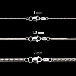 May include: Three silver snake chains with lobster claw clasps, each marked 925. The chains are labelled with widths of 1 mm, 1.5 mm, and 2 mm. The metallic silver chains feature a smooth, interlocking link design and are displayed horizontally.