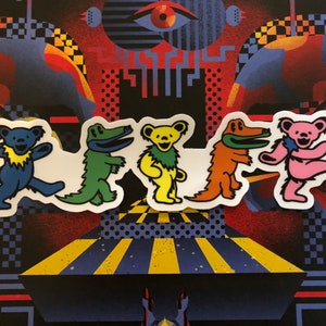 Puede incluir: Cinco pegatinas de osos de dibujos animados de colores. Los osos están en fila y todos llevan ropa de diferentes colores. Los osos sonríen y tienen una expresión feliz en sus caras.