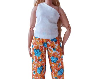 May include: A doll wearing a white one-shoulder top and orange and blue floral print pants.