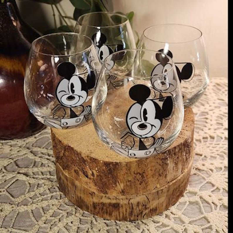 Puede incluir: Juego de cuatro copas de vino sin tallo transparentes. Cada copa presenta un dise&ntilde;o de personaje de dibujos animados en blanco y negro. Las copas se exhiben sobre una base de madera r&uacute;stica. Perfecto para una fiesta tem&aacute;tica o uso diario.