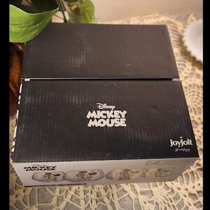 Puede incluir: Una caja negra con el logotipo de Disney Mickey Mouse en blanco. La caja est&aacute; hecha de cart&oacute;n corrugado y tiene un logotipo de Joyjolt en el lateral. La caja contiene un juego de platos con el tema de Mickey Mouse.