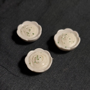 Op de afbeelding: Drie kleine witte kommen gevuld met witte aardappelpuree, gegarneerd met groene bieslook.