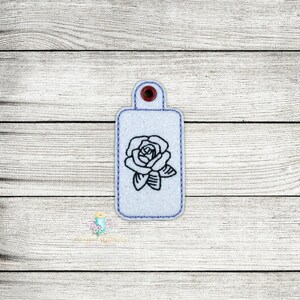 May include: White rectangular key chain with a black outline and a single black rose design.