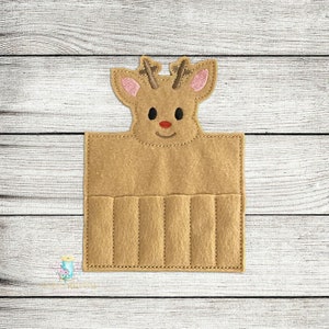 May include: A brown felt reindeer head with pink ears and a red nose. The reindeer head has six slots for holding items, such as lipstick or lip gloss.