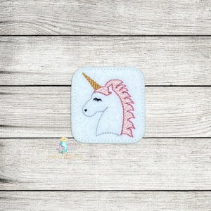 Puede incluir: Parche de fieltro blanco con una cabeza de unicornio bordada. El unicornio tiene una crin rosa y un cuerno dorado.