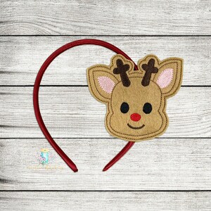 May include: A red headband with a felt reindeer face attached. The reindeer has brown fur, a red nose, and black eyes.