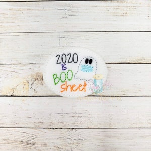 May include: White felt circle with the text "2020 is BOO sheet" in colorful embroidery. A ghost with a face mask is embroidered on the right side of the circle.