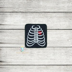 May include: A black embroidered patch with a white outline of a ribcage and a red heart in the center.