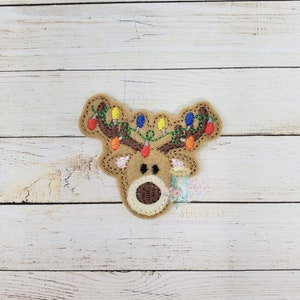 May include: A brown felt reindeer applique with a string of colorful lights around its antlers. The lights are red, yellow, blue, and green.