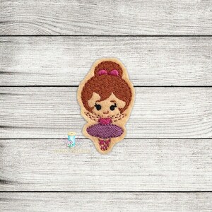 Peut inclure: Patch brodé d'une ballerine avec des cheveux bruns, un tutu violet et des chaussures roses.