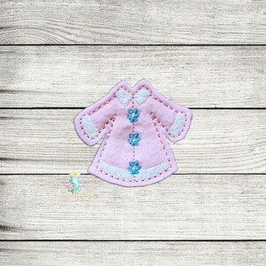 May include: A pink felt applique of a dress with white trim and blue flower embroidery.