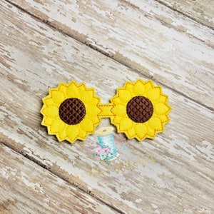 May include: A pair of felt sunflower glasses with yellow petals, brown centers, and a yellow connecting piece.