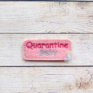 May include: Pink felt patch with the text "Quarantine Baby" embroidered in pink and silver thread.