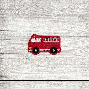 Puede incluir: Aplique de camión de bomberos de fieltro rojo con ruedas negras y detalles blancos.