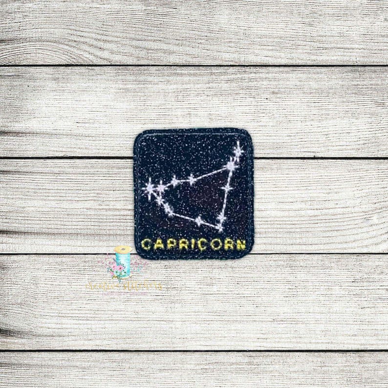 May include: A black and white embroidered patch with a constellation design and the word "Capricorn" in yellow lettering.