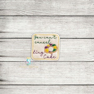 May include: A square felt patch with the text "You can't cancel king cake" and a purple, yellow, and green king cake illustration.