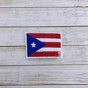 May include: A small embroidered patch featuring the flag of Puerto Rico. The flag is red, white, and blue with a white star in the blue triangle.