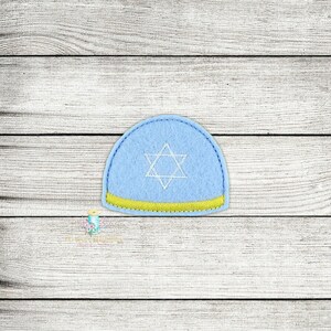 Peut inclure: Une kippa en feutre bleu clair avec une bordure jaune et une étoile de David brodée en blanc.