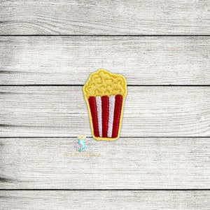 May include: A yellow and red embroidered patch of a popcorn bucket with white stripes.
