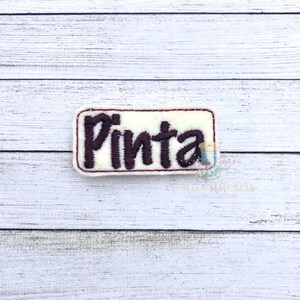 May include: A white rectangular patch with a brown embroidered word "Pinta" on it.