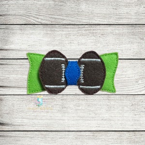 May include: A brown and white football-shaped bow tie with a blue center, attached to a green felt bow.