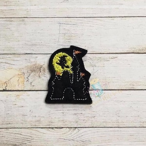 Può includere: Applique in feltro nero di una casa infestata con una luna gialla e una strega che vola su una scopa.