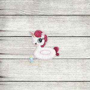 Puede incluir: Flotador de piscina de unicornio blanco con melena y cola rosas. El unicornio tiene un solo cuerno y ojos grandes y negros.