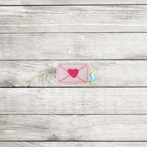 May include: A pink envelope with a pink heart in the center. The envelope is on a white wood background.