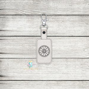 May include: A white leather keychain with a silver key ring and a black wheel design.