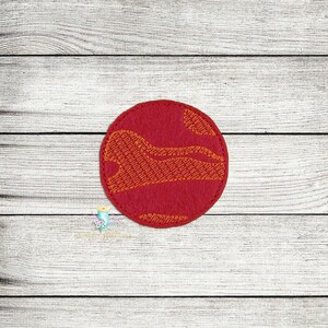 May include: Red felt circle with an orange embroidered design resembling a planet.