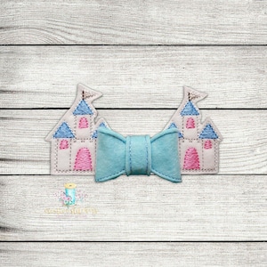 May include: A light blue bow with two white castle appliques with pink accents. The castles have blue roofs and white flags.