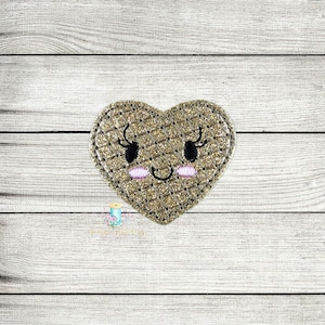 May include: A gold glitter heart with a smiling face, eyelashes, and pink cheeks. The heart is a felt appliqué with a quilted texture.
