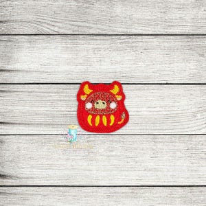 May include: Red and yellow embroidered felt applique of a cartoon ox with a smiling face.