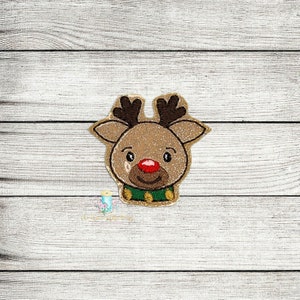 May include: A brown reindeer face with a red nose and green collar. The reindeer has a smiling expression and large brown eyes.