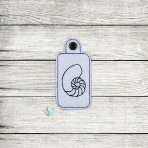Può includere: Un'etichetta per chiavi rettangolare bianca con un contorno nero di una conchiglia di nautilus. L'etichetta per chiavi ha un piccolo foro nella parte superiore per attaccare un portachiavi.
