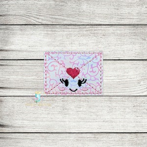 Peut inclure: Une enveloppe brodée rose et blanche avec un cœur et un visage souriant. L'enveloppe présente un motif décoratif et est bordée de coutures roses. Le cœur rouge et le visage ont des cils noirs et un sourire courbé.