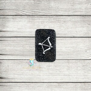 May include: A black square-shaped coaster with a white bow and arrow design.