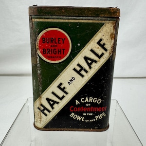 May include: Vintage rectangular tobacco tin with a green, black, and white design. The tin features the text "BURLEY AND BRIGHT TOBACCO" in a red circle and "HALF AND HALF" in bold white letters. The text "A CARGO OF CONTENTMENT IN THE BOWL OF ANY PIPE" is also visible.